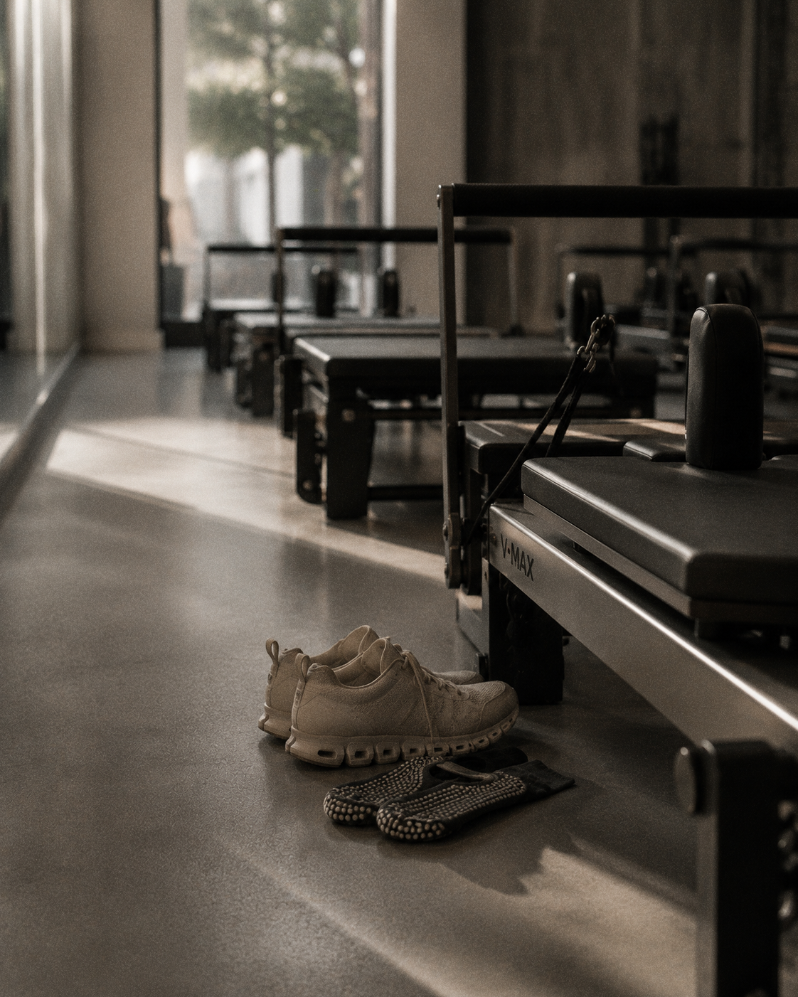 Shoes and grip socks left beside reformers in a quiet studio