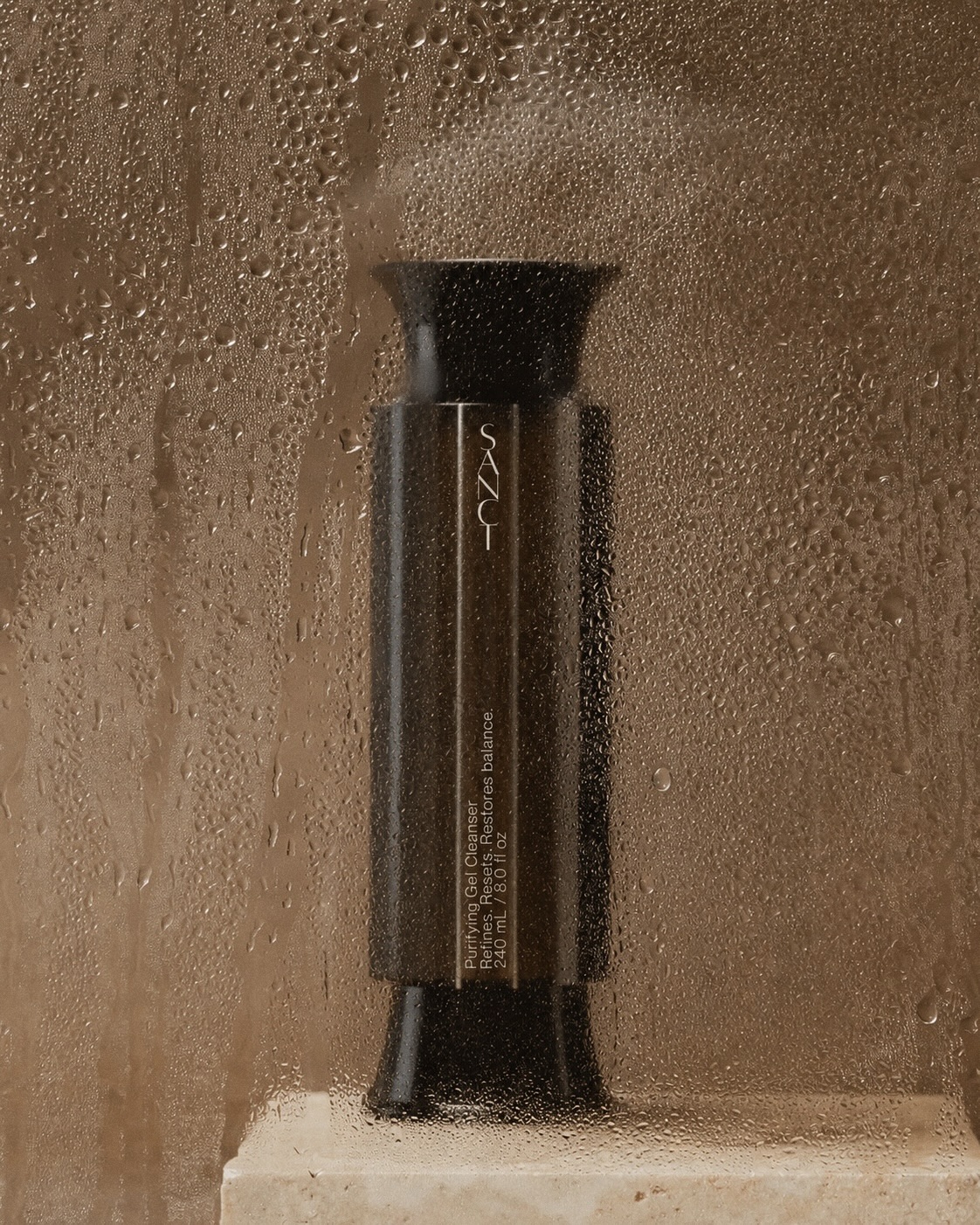 The Sanct cleanser on a travertine ledge behind a steamed glass panel